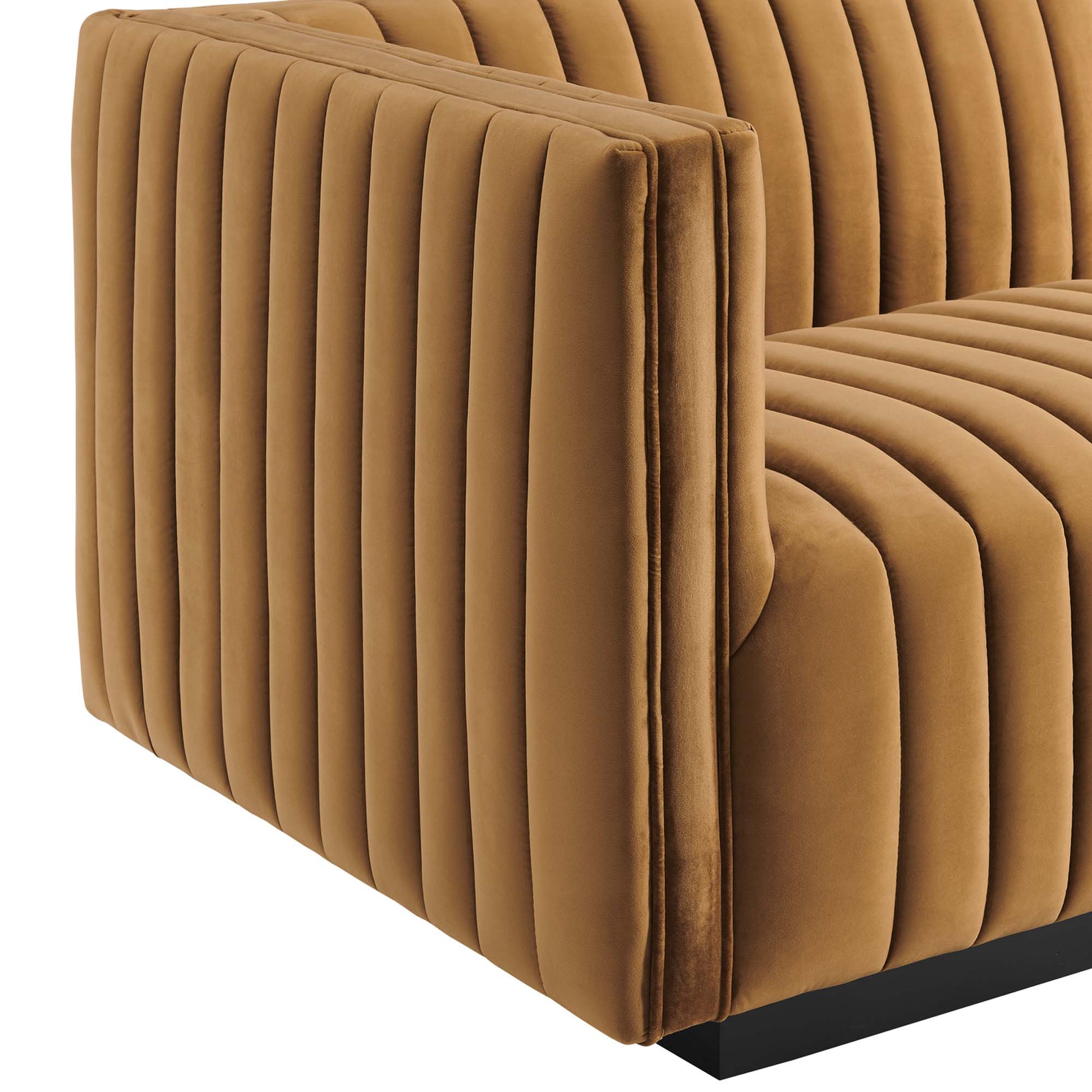 Cognac velvet left-arm chair with vertical channel tufting on the arms and seat, modern blocky silhouette, black base.
