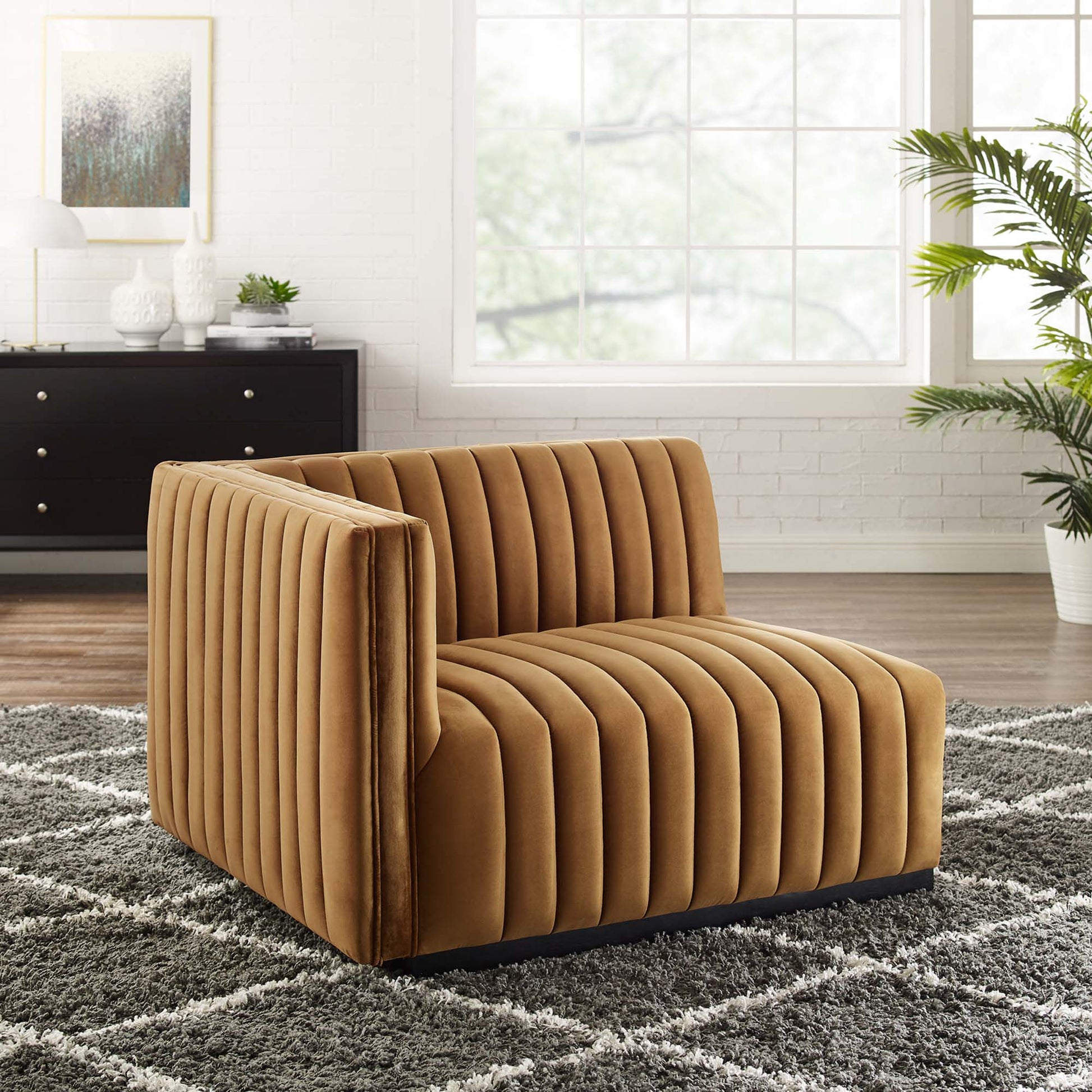 Camel velvet channel-tufted lounge chair with low black legs in a bright living room.