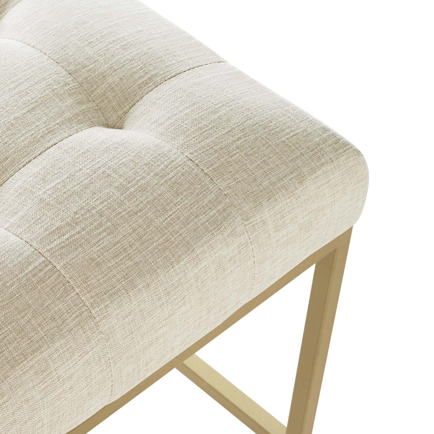 Beige linen-tufted stool with light gold wooden legs, rectangular modern glam seating.