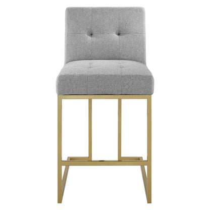 Gray tufted fabric counter stool with a gold metal frame, backrest and footrest, modern counter seating.