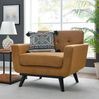 Cognac velvet mid-century armchair with black tapered legs and a geometric black-white pillow in a living room.