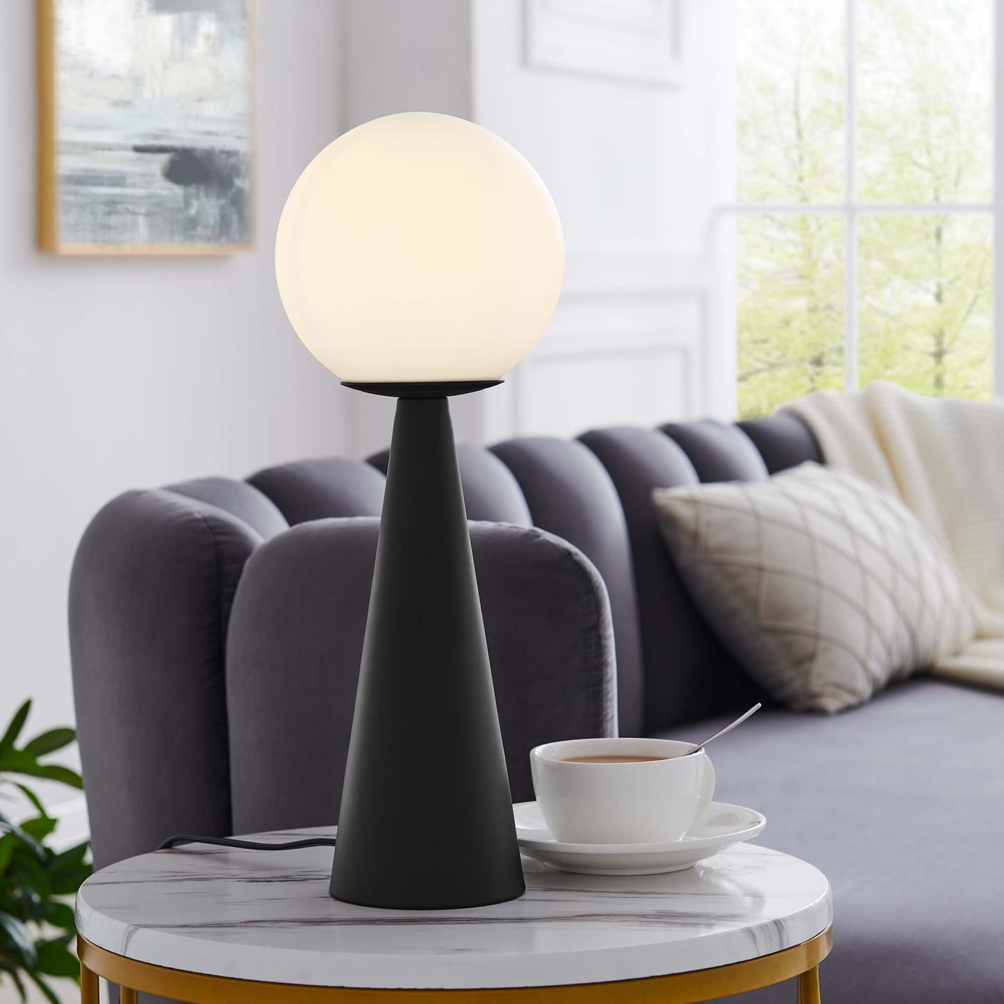 Modern black glass globe table lamp with a frosted white globe on a marble-top side table in a bright living room.