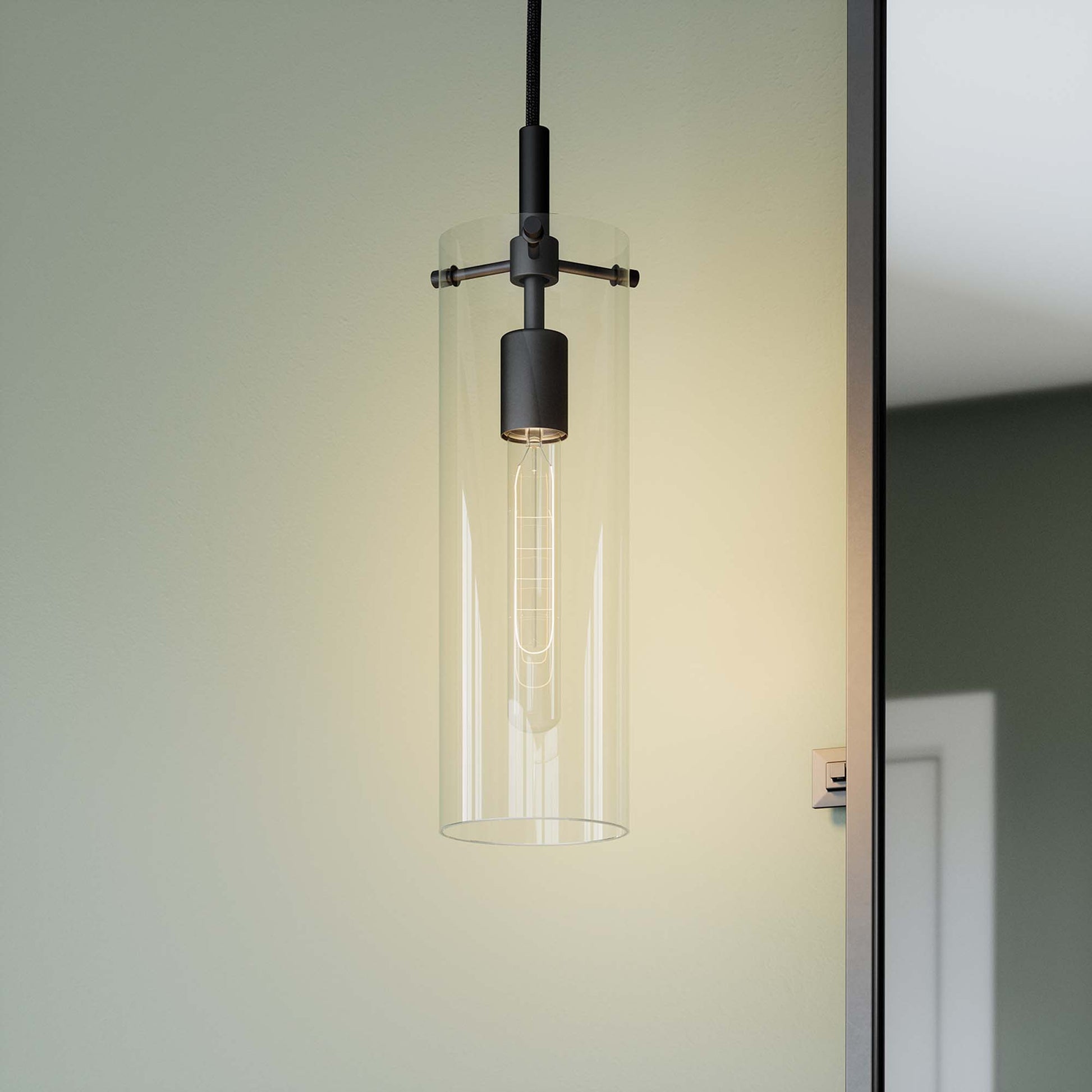 Clear glass cylindrical pendant light with black metal hardware and Edison filament bulb.
