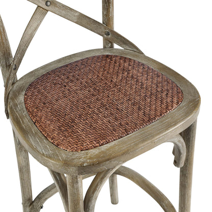 Gray-washed wooden bar stool with a rounded frame and brown woven cane seat, rustic vintage style.