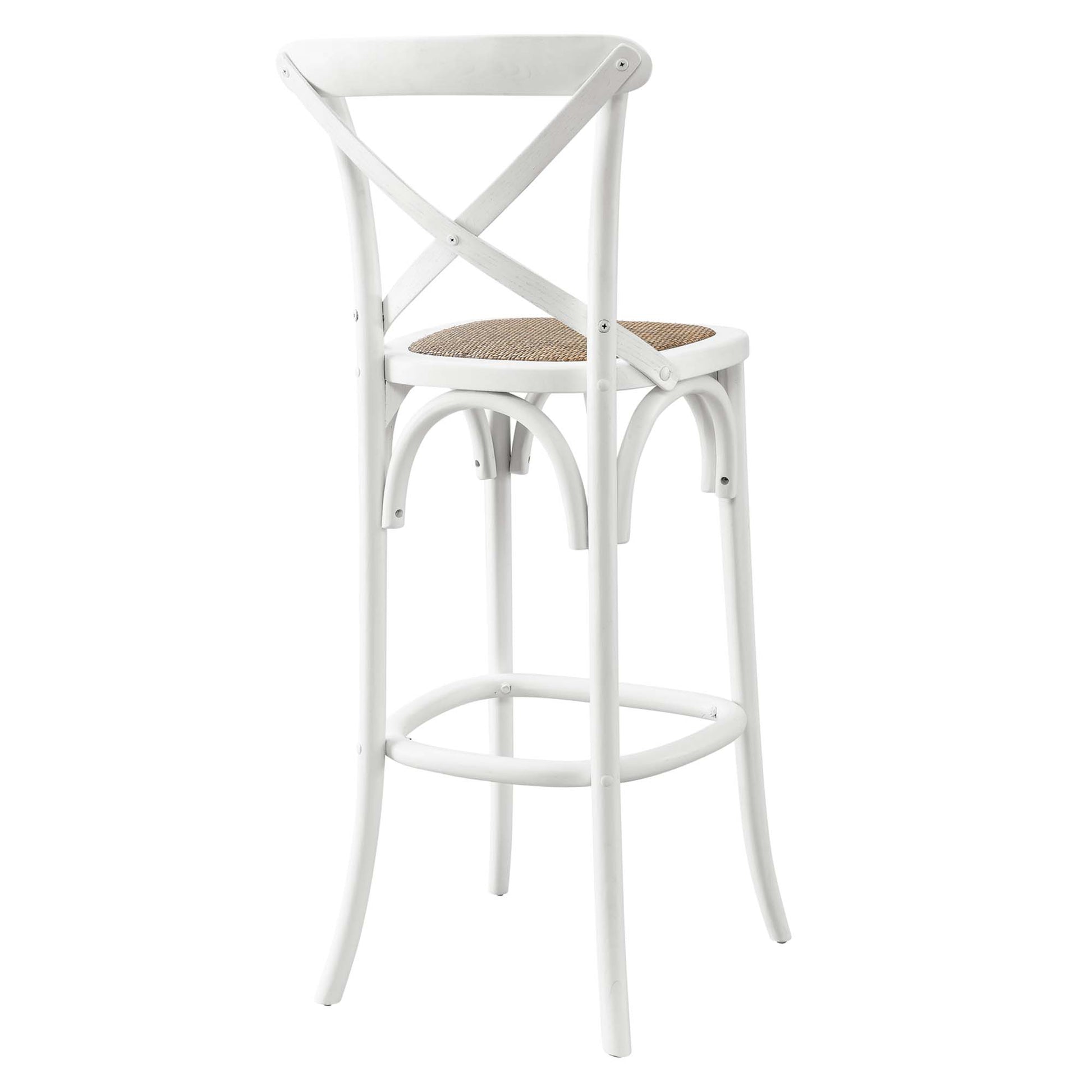 White metal bar stool with X-back, woven natural rattan seat, curved legs and footrest; industrial farmhouse style.
