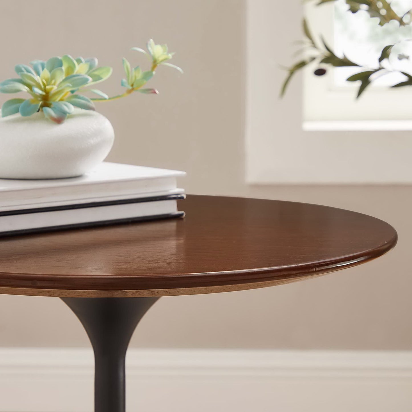 Round walnut-finish wood side table with a black pedestal base; mid-century style.