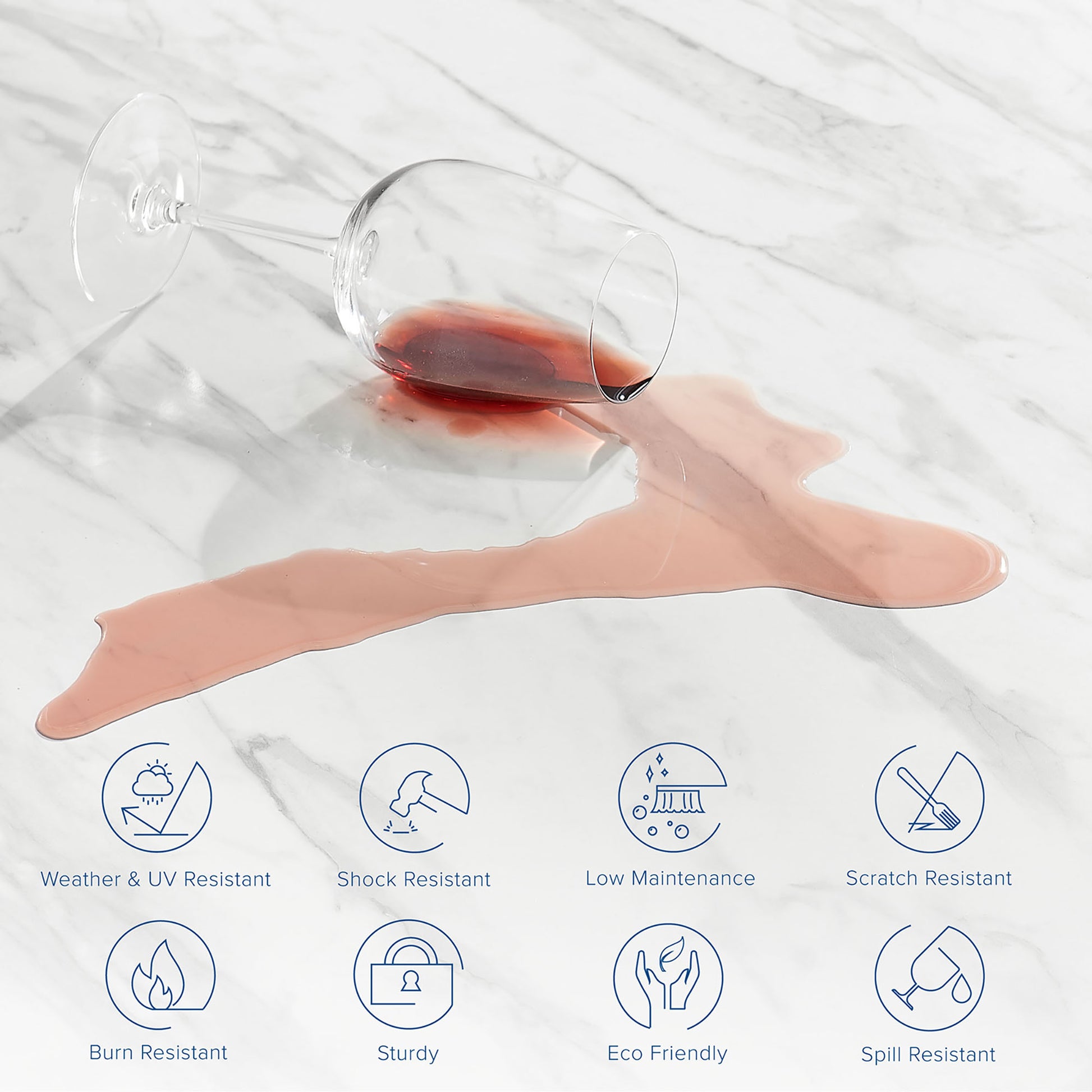 Clear stemmed wine glass tipped over on a white artificial marble dining table top, with red wine spill forming a pink puddle.