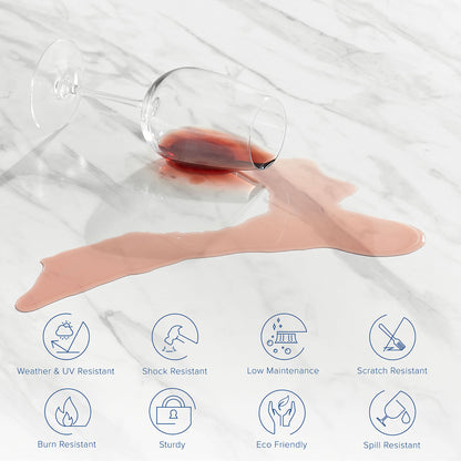 Clear stemmed wine glass tipped over on a white artificial marble dining table top, with red wine spill forming a pink puddle.
