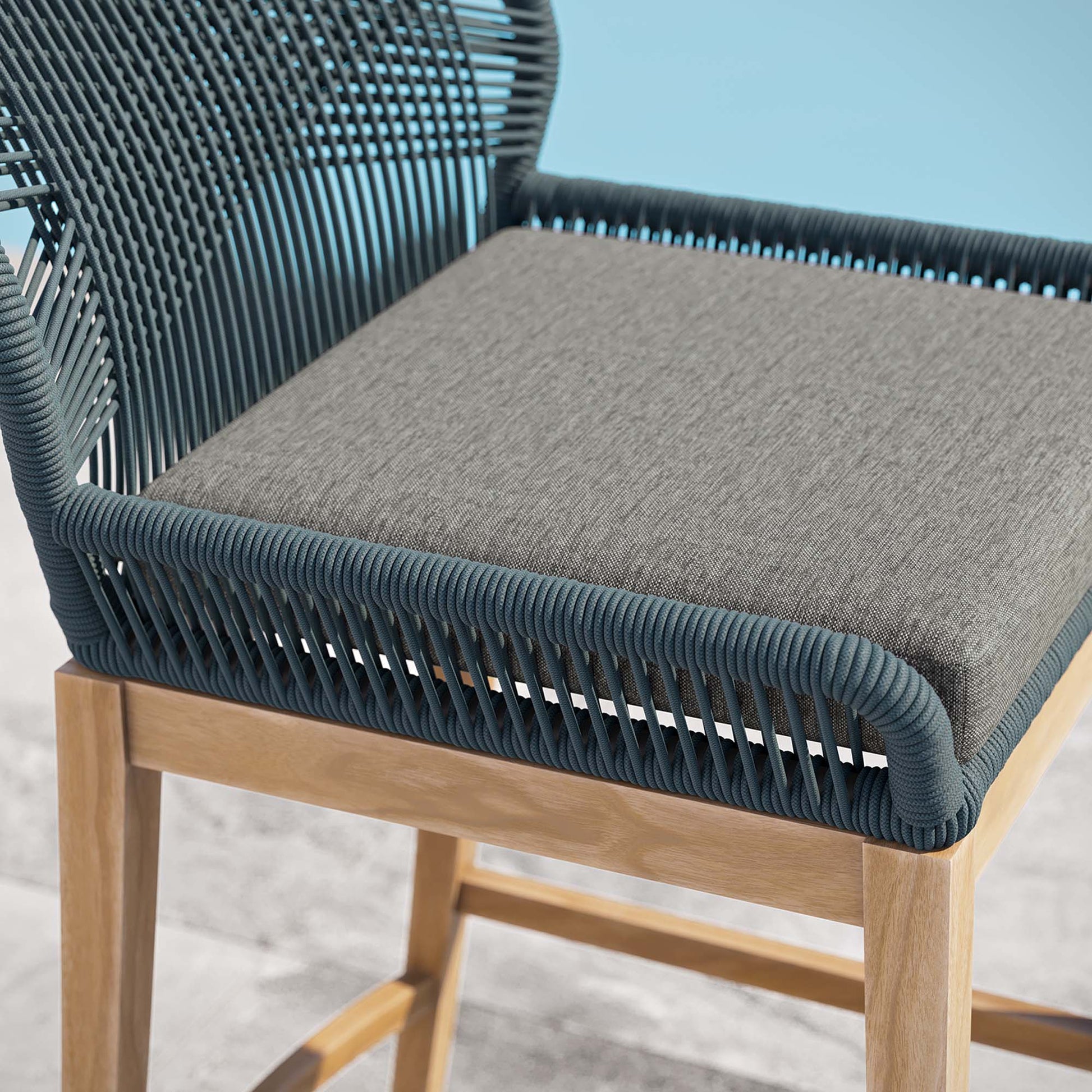 Blue woven rope outdoor teak wood bar stool with grey cushion.