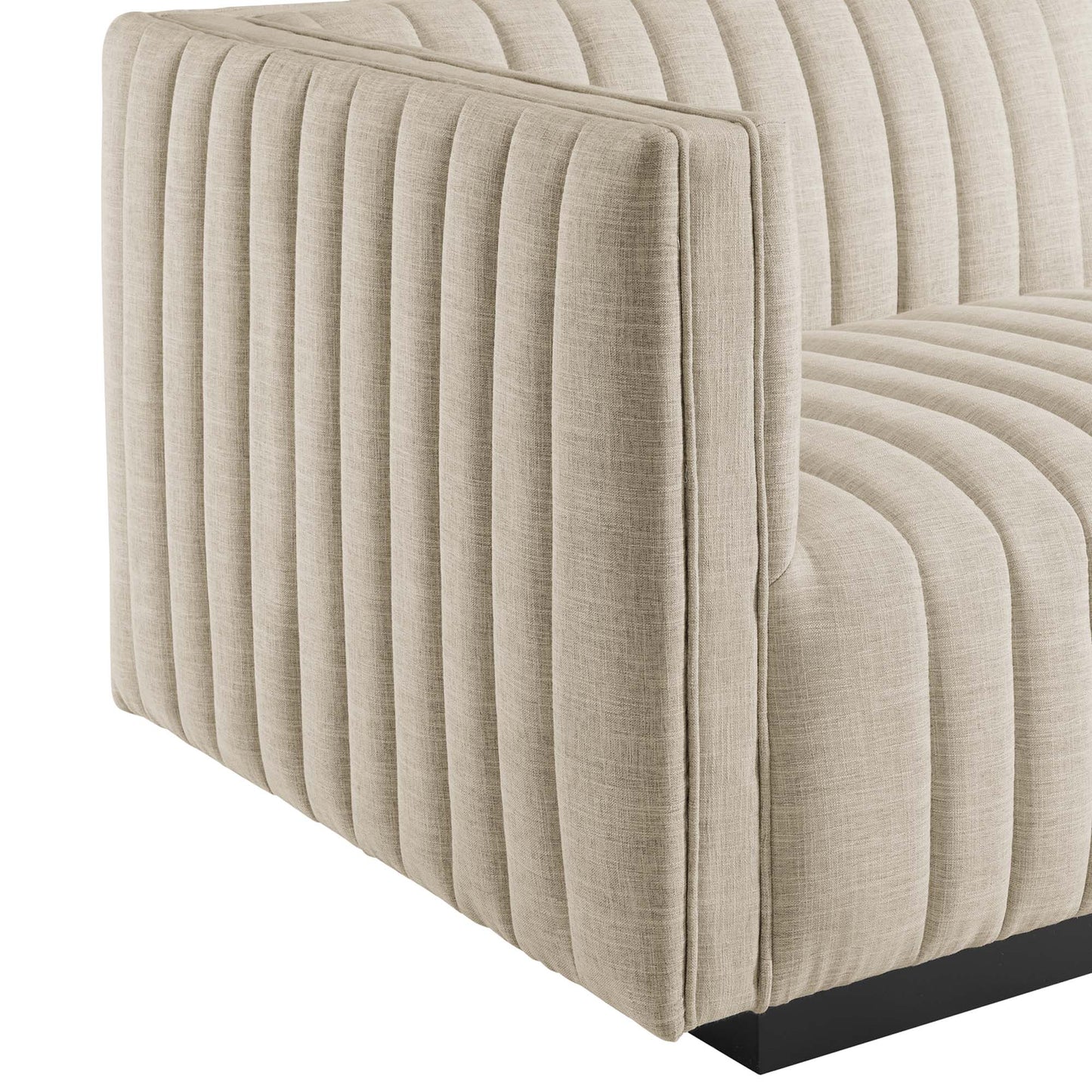 Beige fabric sofa with vertical channel tufting, square arms, and a low black rectangular base.