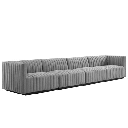 Long gray fabric sectional with vertical channel tufting, low black base, modern living-room sofa.