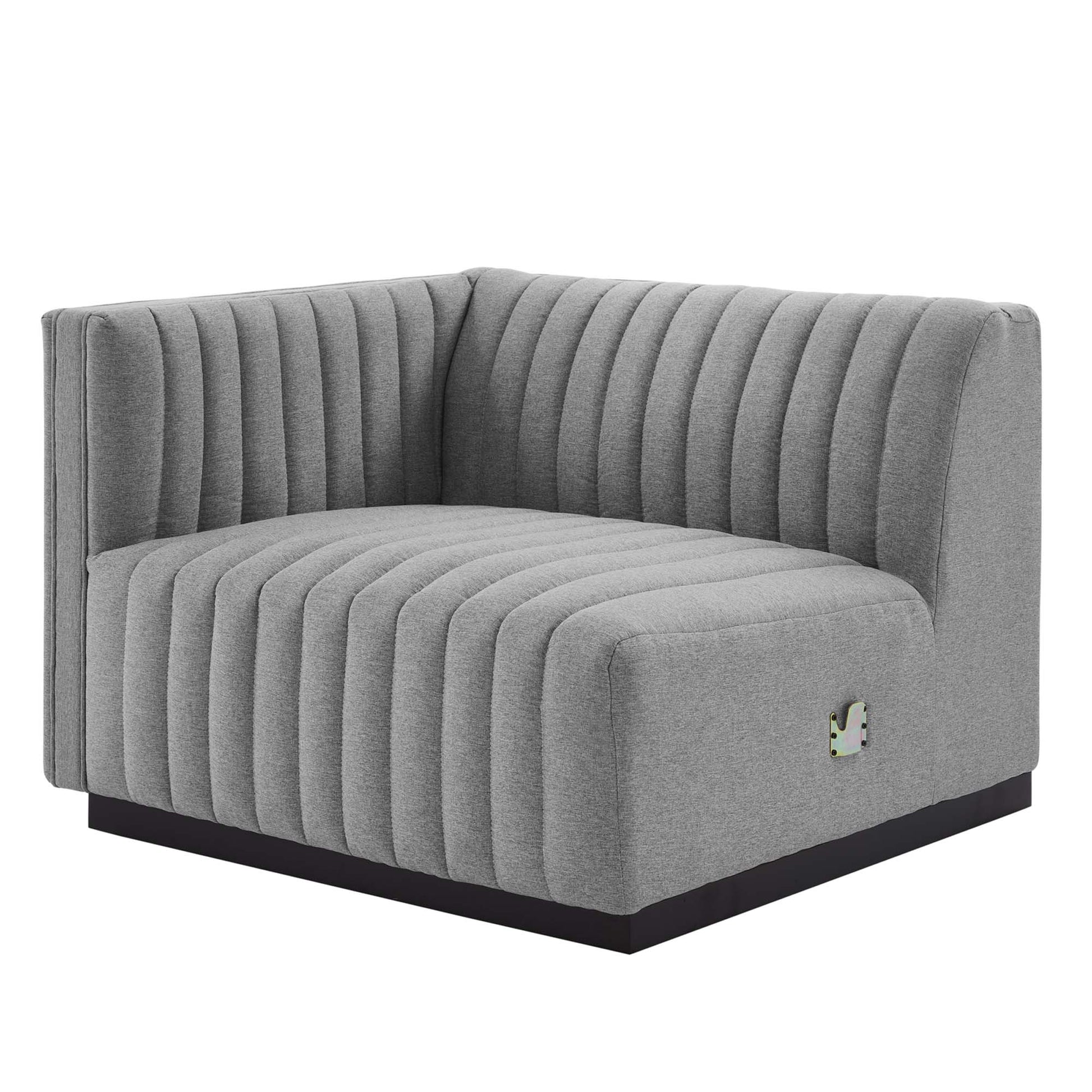 Gray L-shaped corner sofa with vertical channel tufting and a low black base.