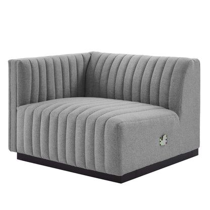 Gray L-shaped corner sofa with vertical channel tufting and a low black base.
