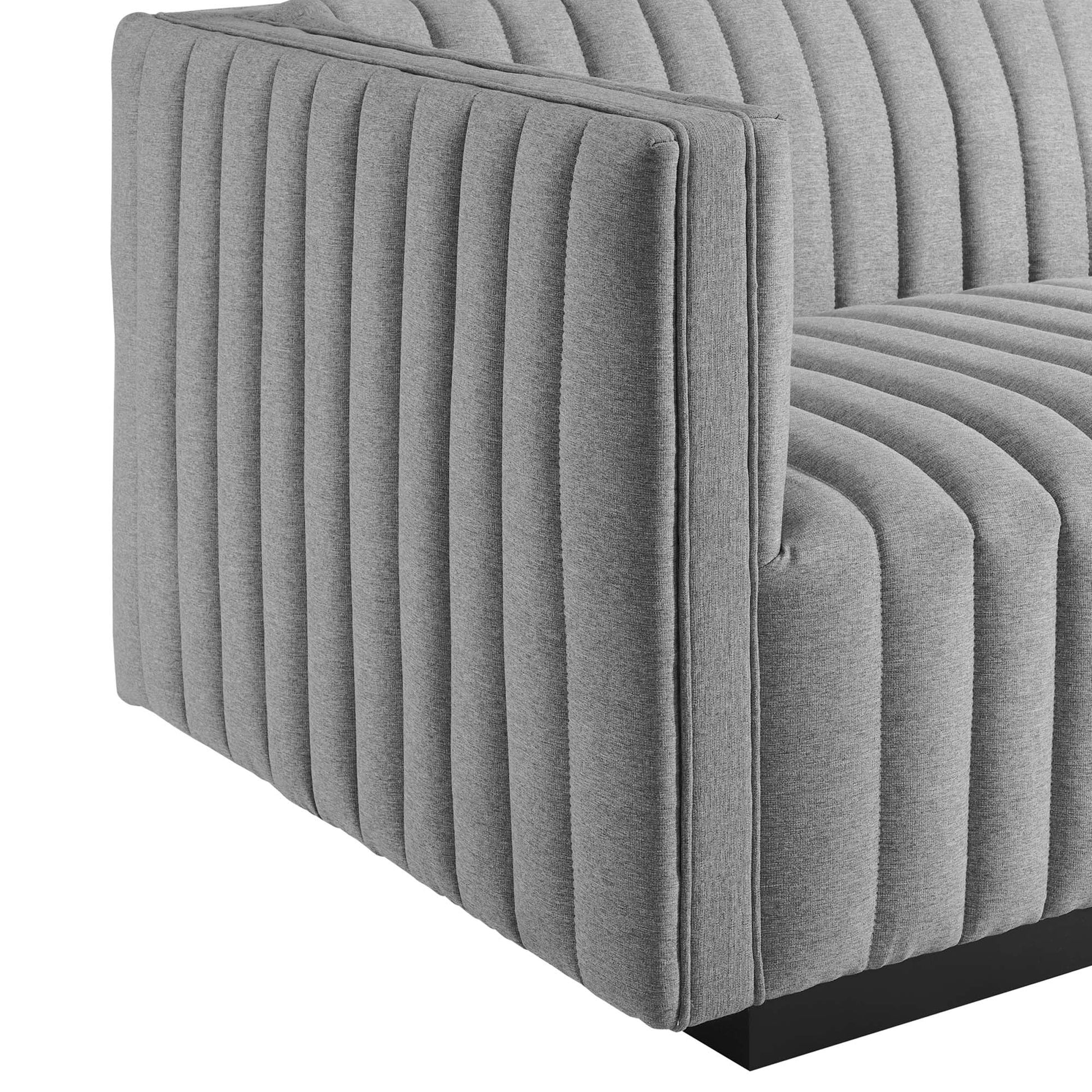 Gray fabric sofa with vertical channel tufting on arms and seat, modern lounge style, black low-profile base.
