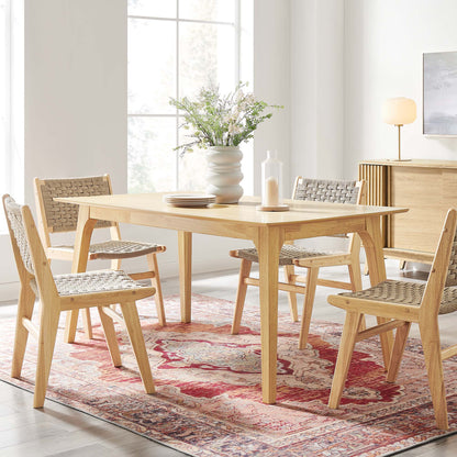 Light oak rectangle dining table in a bright, modern dining room; vase of flowers on the table, red rug.