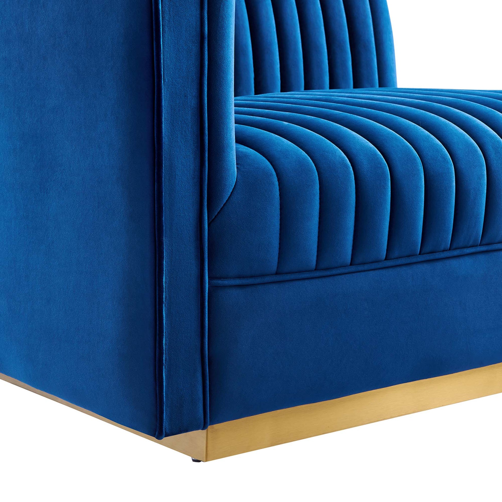 Navy blue velvet sofa with vertical channel tufting and gold base trim.