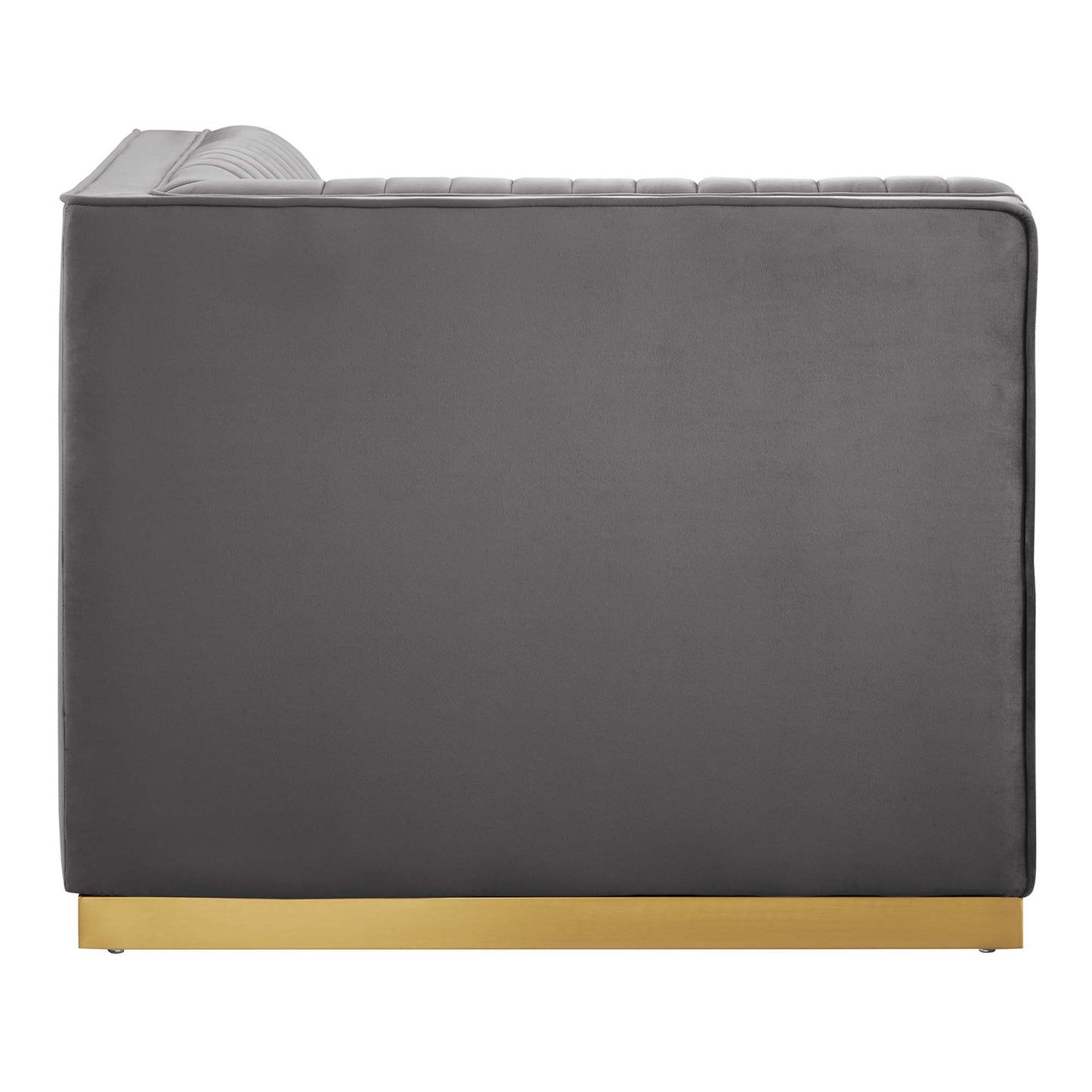 Grey velvet sofa with curved, ribbed headrest and gold-plated plinth base; modern, low-profile lounge style.