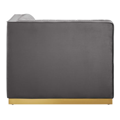 Grey velvet sofa with curved, ribbed headrest and gold-plated plinth base; modern, low-profile lounge style.