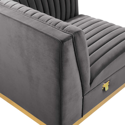 Gray velvet chair with vertical channel tufting, padded arms, and a gold base trim.