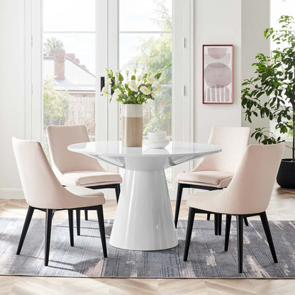 White round pedestal dining table with blush fabric-upholstered chairs in a bright modern dining room.