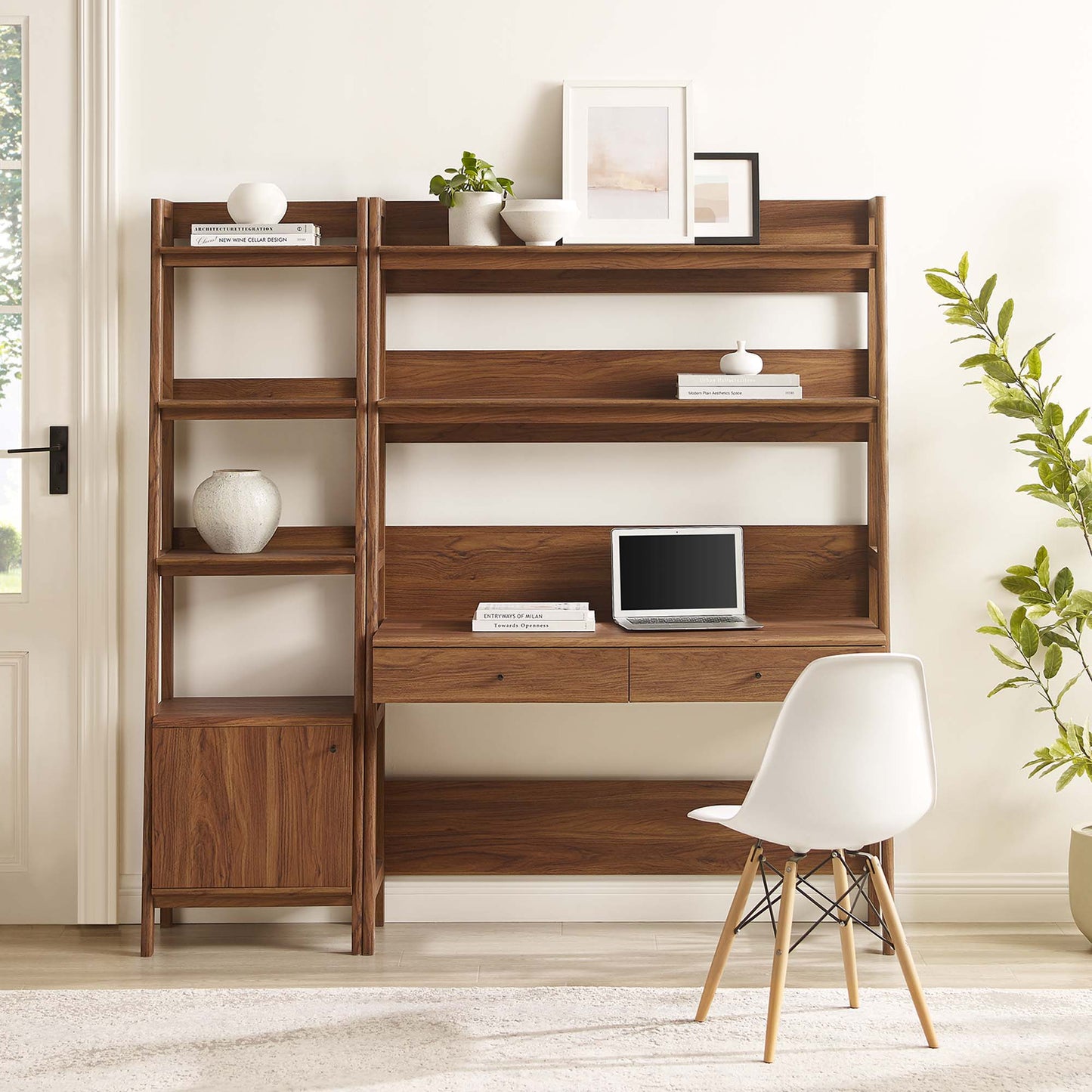 Walnut wood 2-piece desk and bookshelf set with open shelves and drawers; laptop on desk, white chair, plant & framed art.
