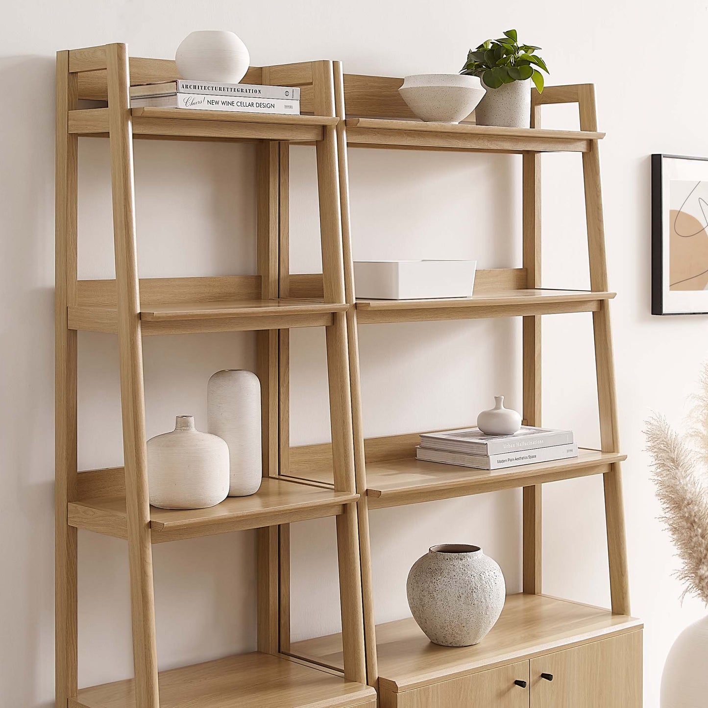 Light oak ladder shelf with open shelves, decor including white vases, bowls, books, a plant, and a bottom cabinet.