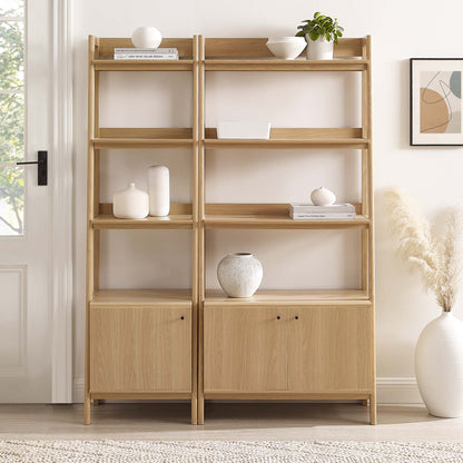 Pair of light oak open-shelving bookcases with bottom cabinets, styled with vases and a plant.
