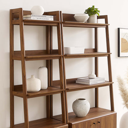 Walnut ladder bookshelf with five open shelves and a bottom cabinet; decorated with white vases, bowls, books and a plant.