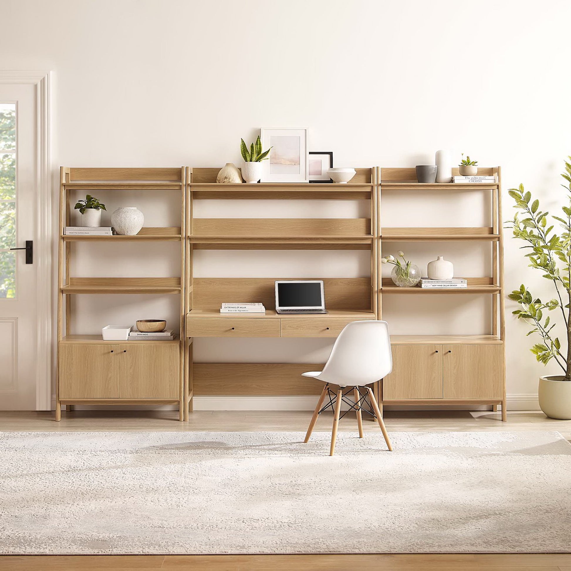 Brown oak modular desk-and-shelf unit with open shelves and lower cupboards, white chair, greenery