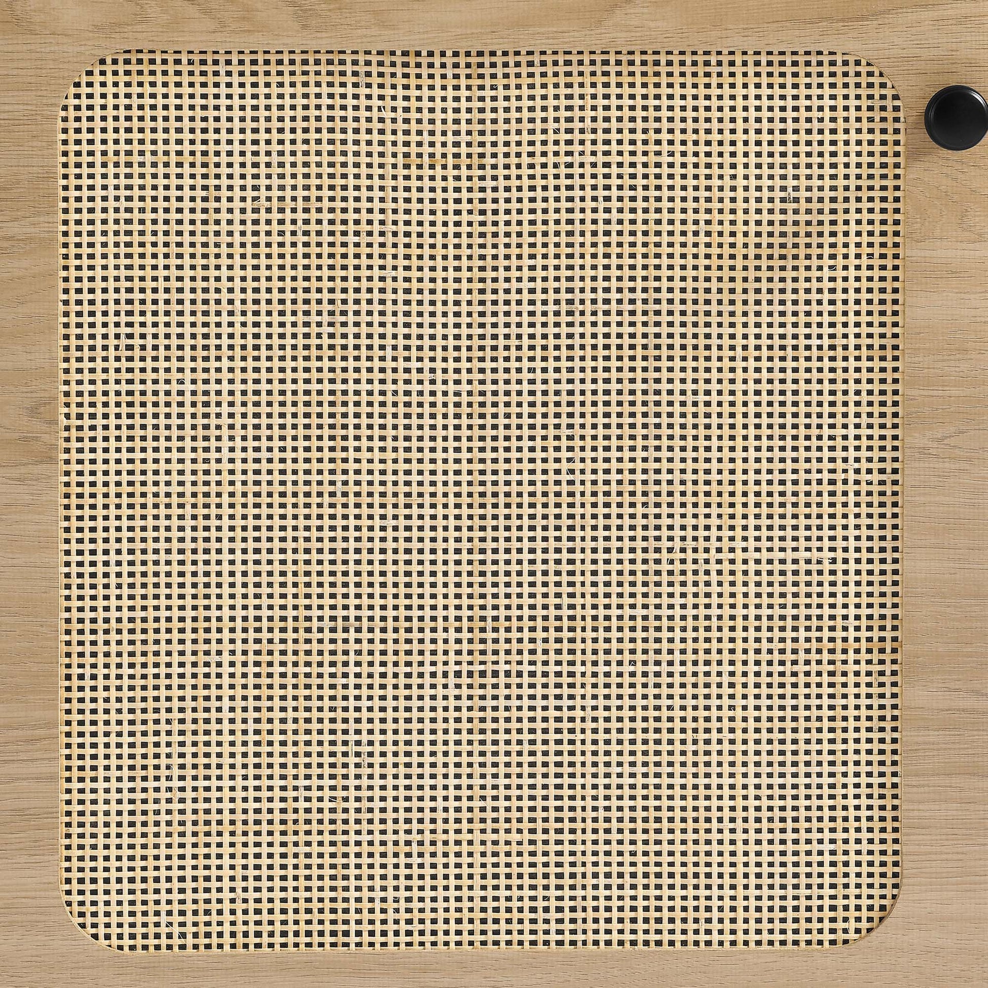 Oak-finish square panel with rounded corners and woven cane grid center; black knob at top-right.