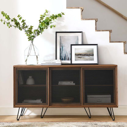 Walnut sideboard with three mesh-front cabinets on hairpin legs, topped with a vase of greenery and framed artwork.