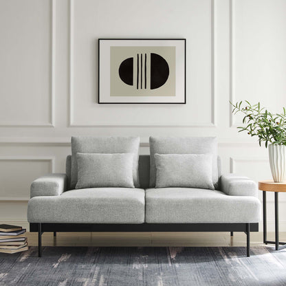 Light gray contemporary loveseat with two cushions, black metal legs, abstract art, plant, books, and blue-gray rug.