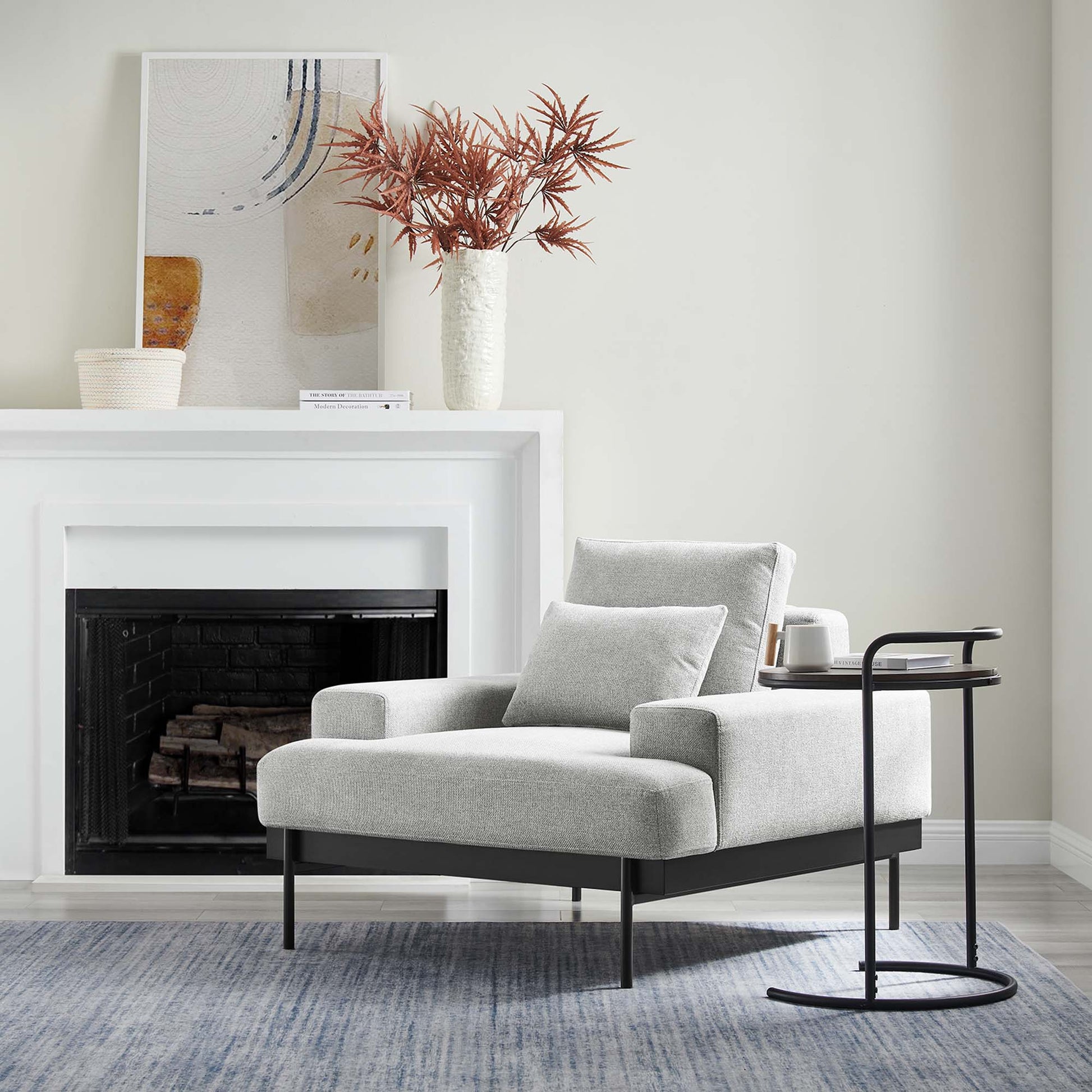 Modern light gray fabric armchair with black metal legs and matching cushion on a blue area rug.