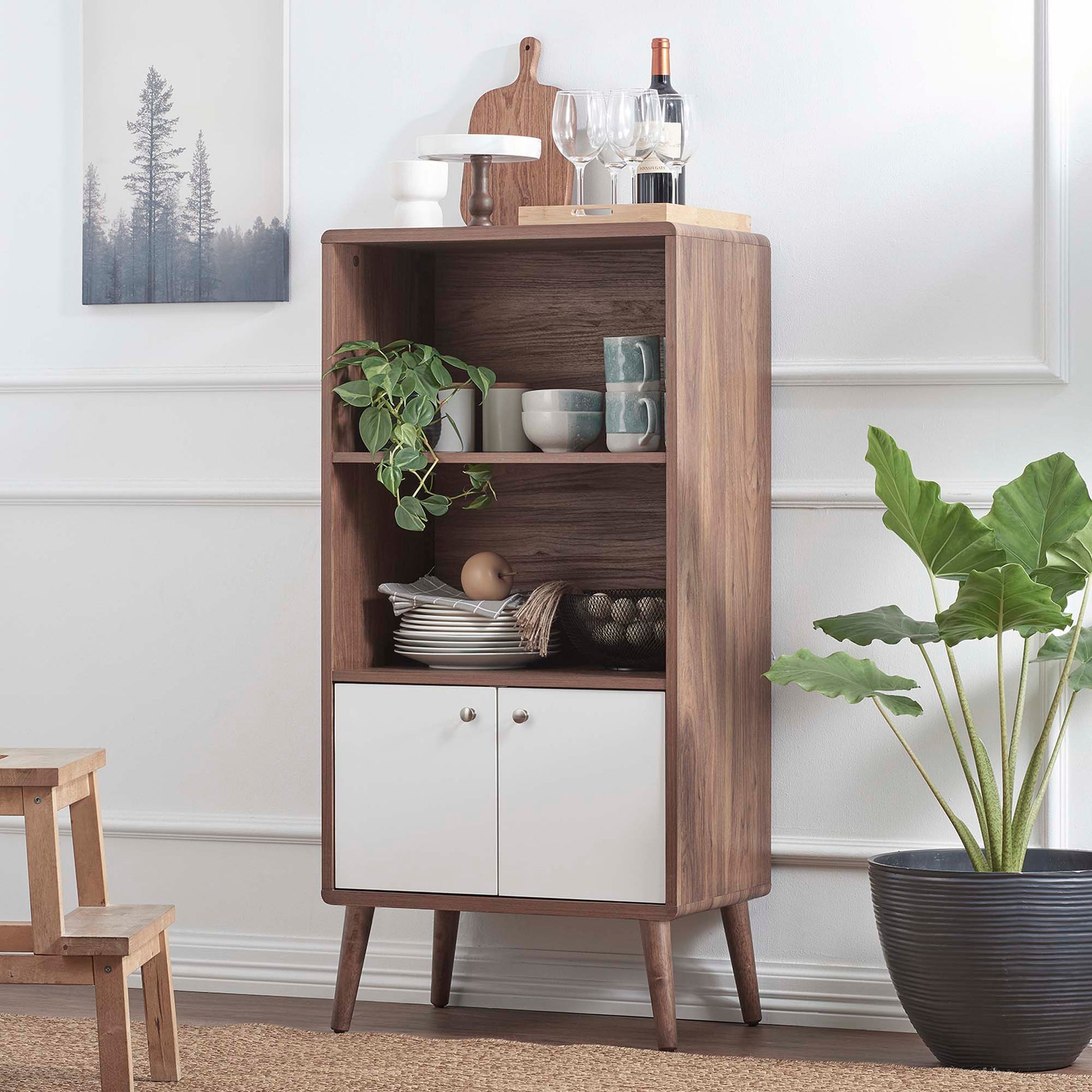 Mid-century walnut display cabinet with white doors and open shelves, showing dishes and a plant, with tapered legs.