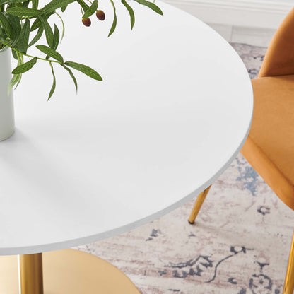 White dining table with gold legs, vase of greenery, and a yellow chair nearby in a mid-century modern setting.