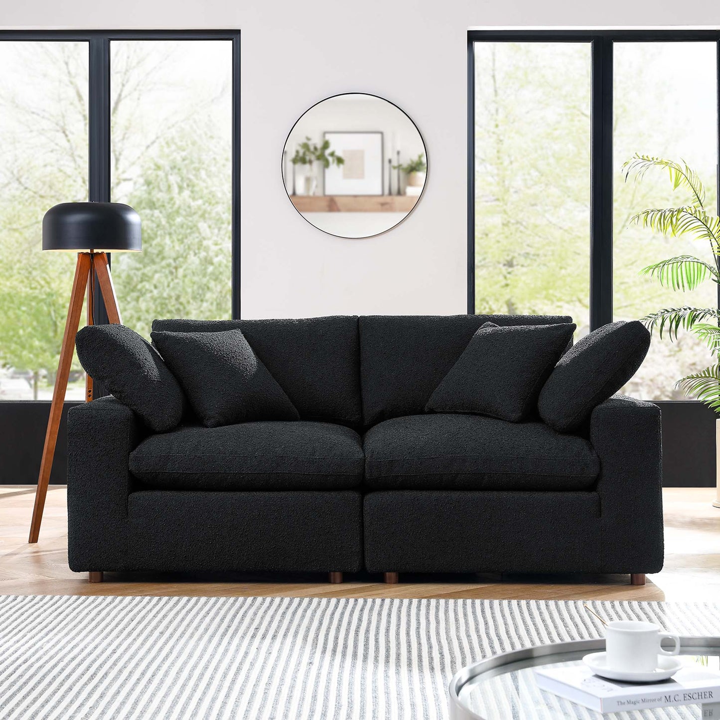 Charcoal boucle fabric loveseat with low-profile arms and wooden legs in a bright modern living room.