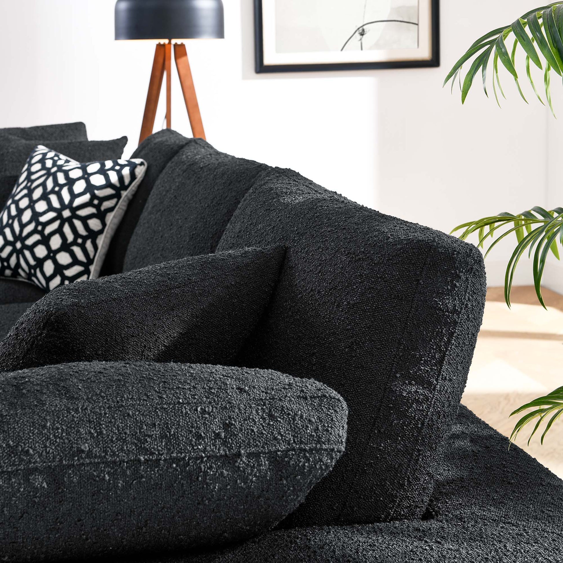 Charcoal boucle fabric 3-seater sofa with plush cushions in a modern living room, paired with a geometric throw pillow.