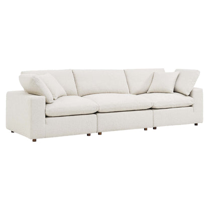 Ivory boucle 3-seat sofa with loose back cushions, low square arms, and wooden legs.