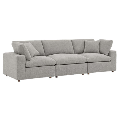 Gray fabric sofa with square arms, three-seat cushions, multiple back cushions, short wooden legs.