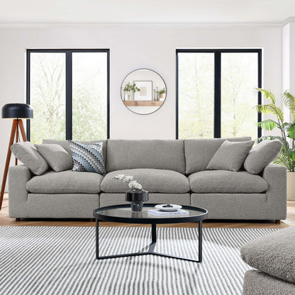 Gray fabric sofa with cushions in a bright modern living room; round black coffee table, striped rug, plants.