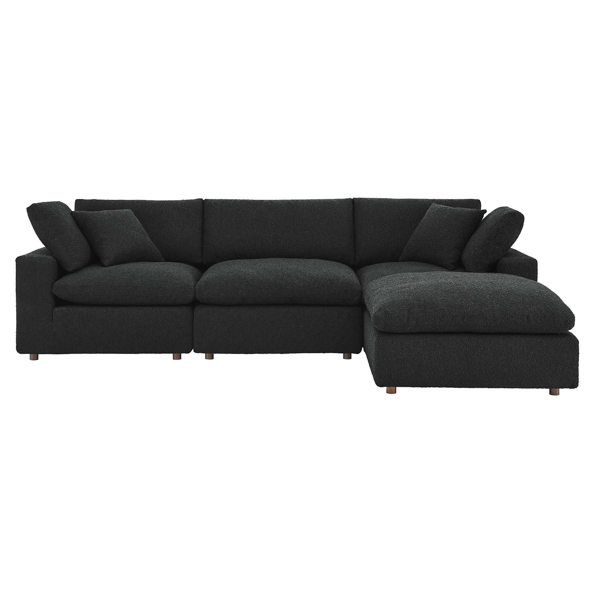 Black sectional sofa with chaise on the right, plush cushions and short wooden legs.