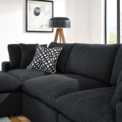 Charcoal textured sectional sofa with a black-and-white geometric pillow, wood tripod lamp, and framed abstract art.