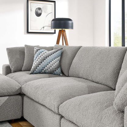 Light gray boucle sectional sofa with a blue-gray geometric pillow and a black-shade tripod floor lamp in a living room.