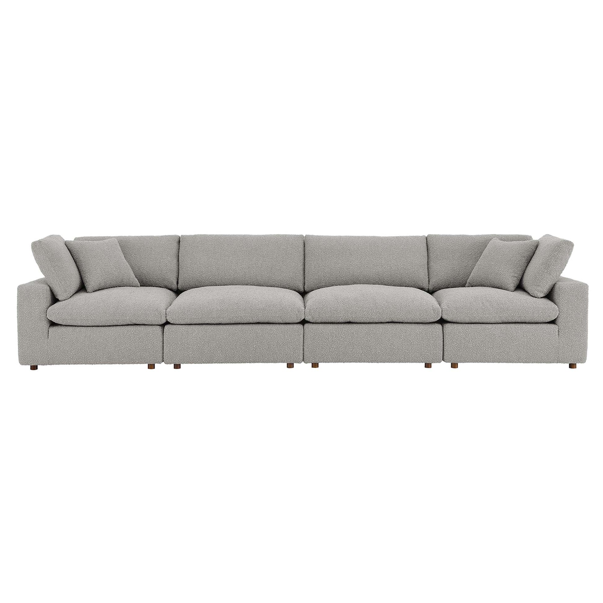 Long light gray boucle fabric sofa with six seat cushions, two throw pillows, low square arms and wooden legs.