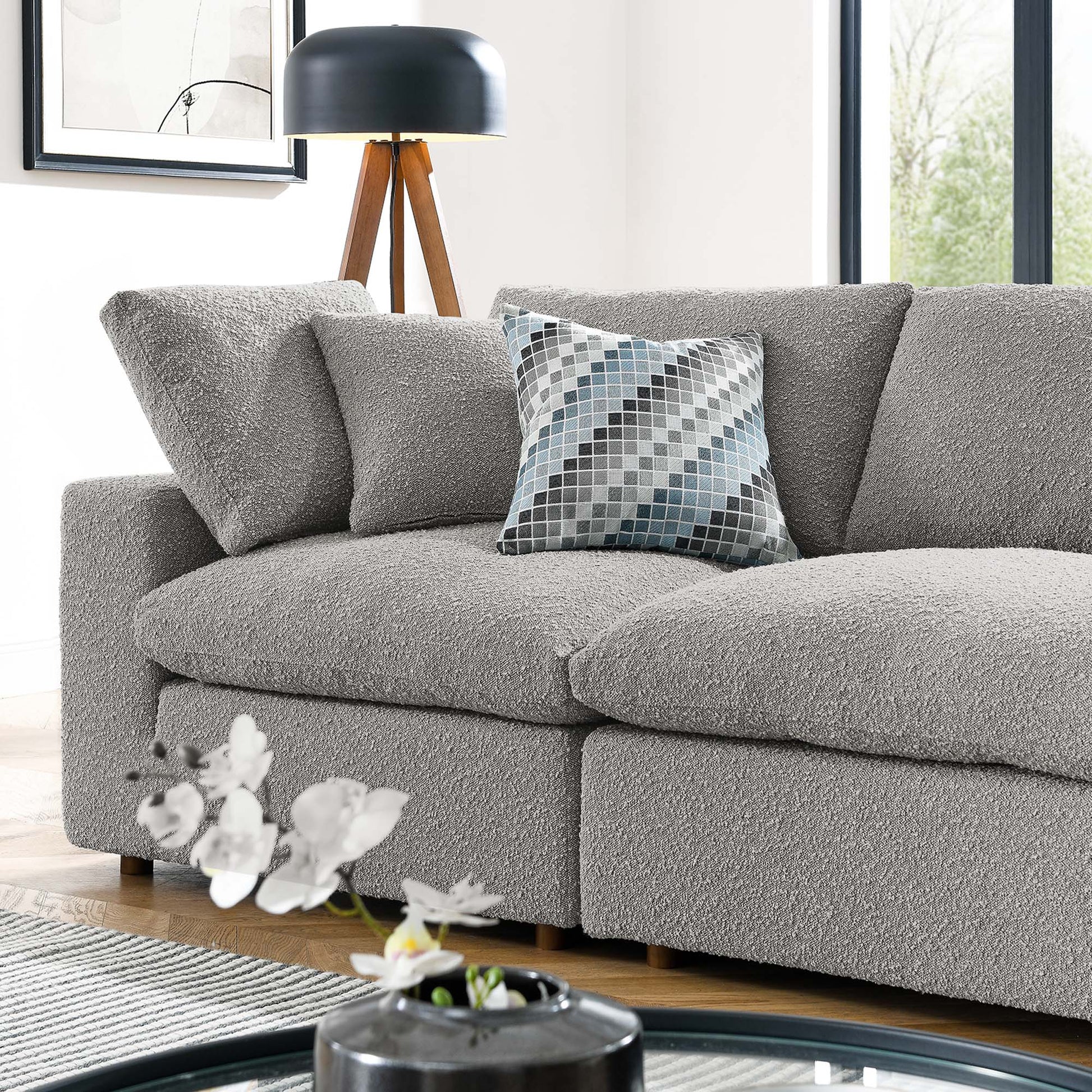 Light gray boucle sofa with textured cushions and a blue-gray geometric pillow in a bright modern living room.