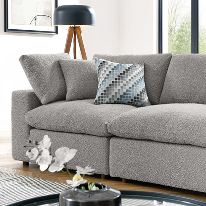 Light gray boucle sofa with textured cushions and a blue-gray geometric pillow in a bright modern living room.