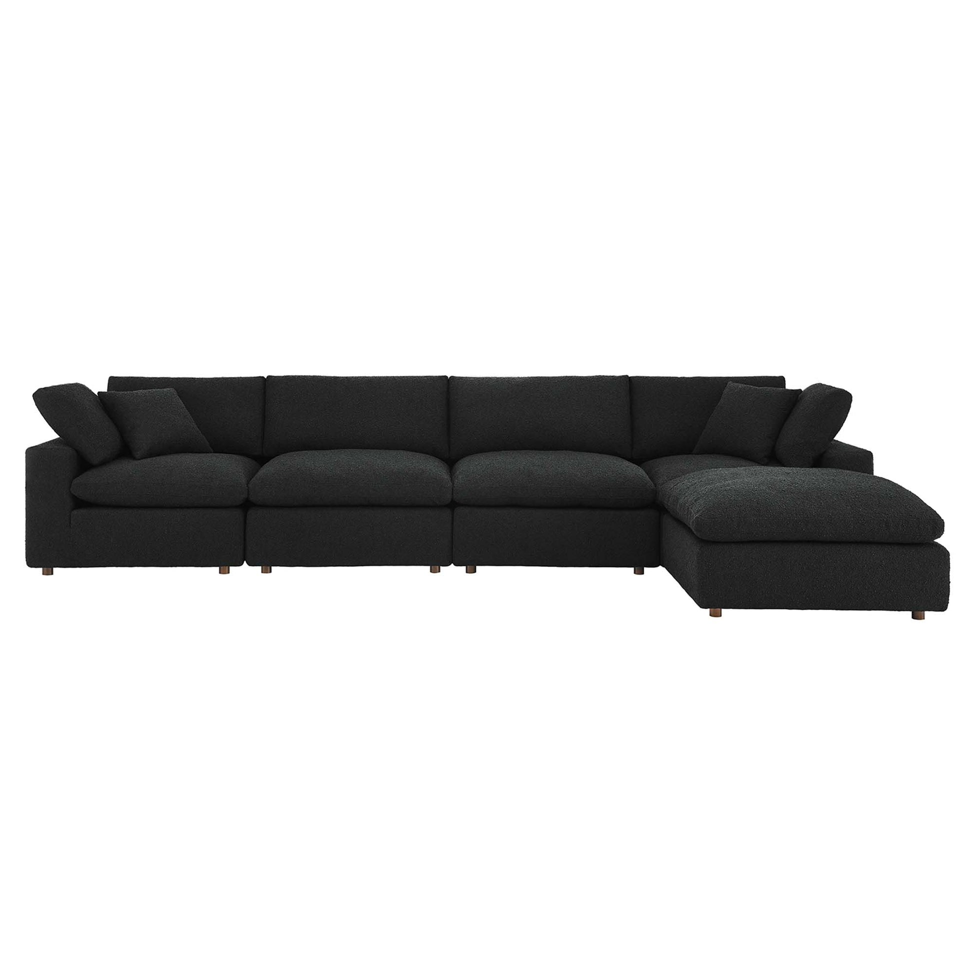Black fabric sectional sofa with chaise on the right, modular sections, plush cushions, low wooden legs.