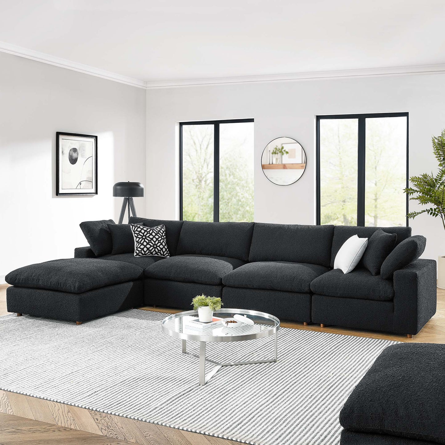 Black boucle fabric L-shaped 5-piece sectional sofa in a modern living room with a round glass coffee table & a striped rug.