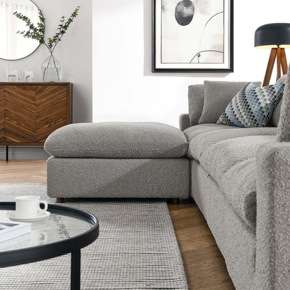 Modern grey textured fabric sectional with chaise, glass coffee table, chevron wood sideboard, gray rug, black-framed art.