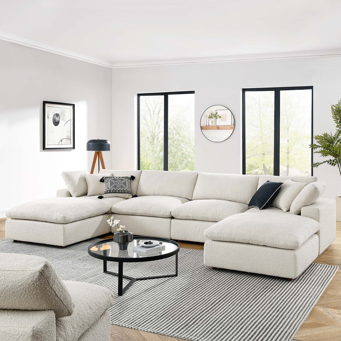 Ivory boucle sectional with chaise lounge in a modern minimalist living room with a round coffee table and striped rug.